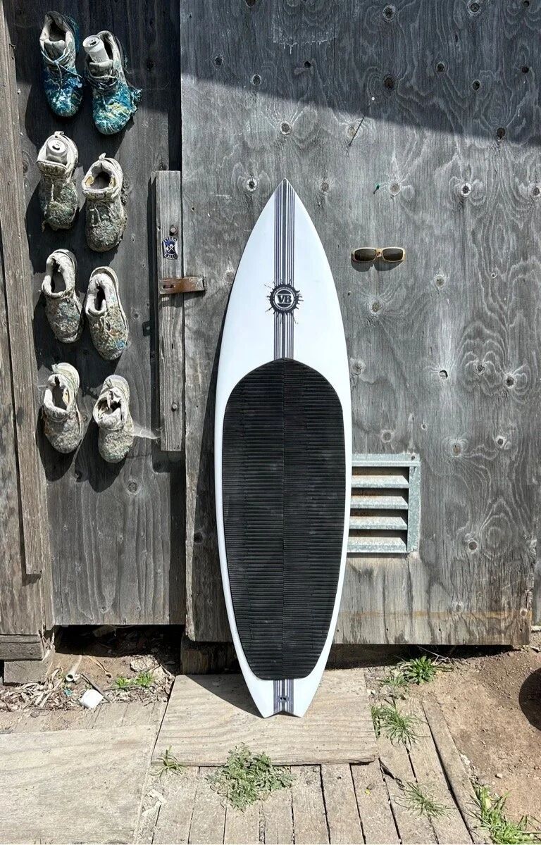 Custom kiteboard by Vince Broglio leaning against a wooden wall